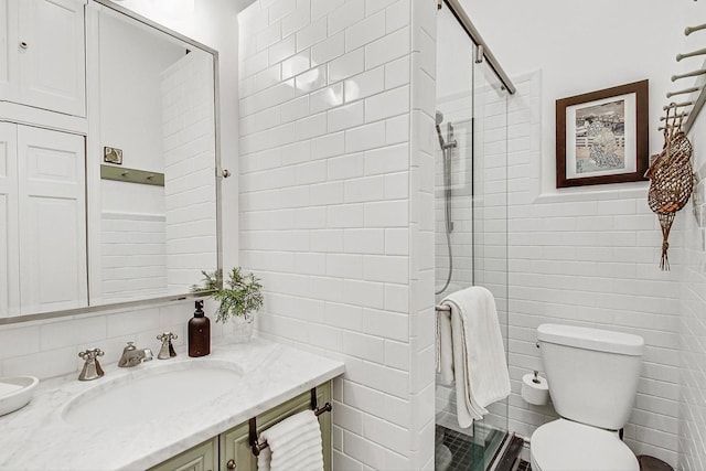 bathroom featuring vanity, tiled shower, tile walls, and toilet