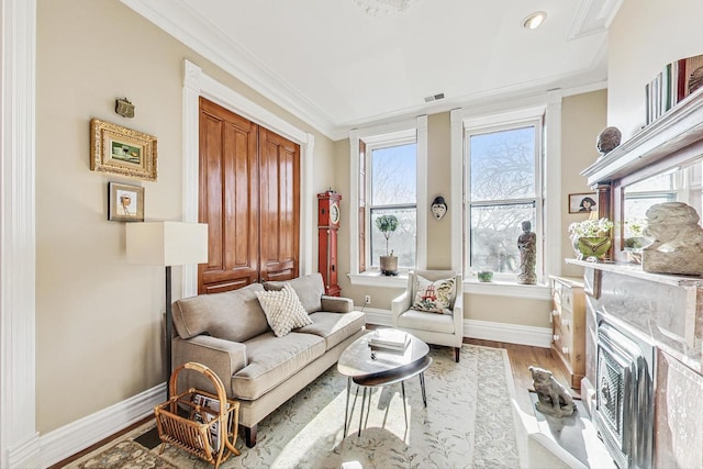 living area with a high end fireplace, ornamental molding, and light hardwood / wood-style floors