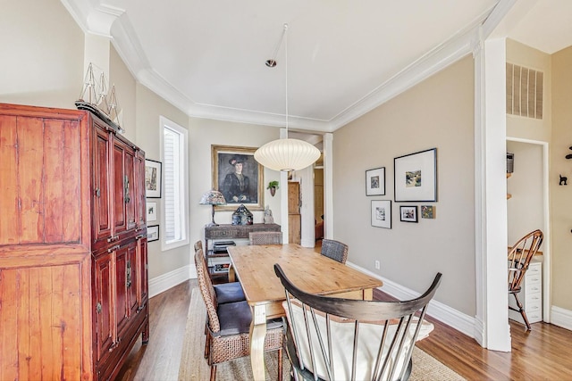 dining area with hardwood / wood-style flooring and crown molding