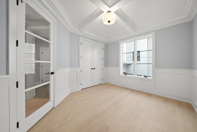 spare room with beam ceiling, ornamental molding, coffered ceiling, and light wood-type flooring