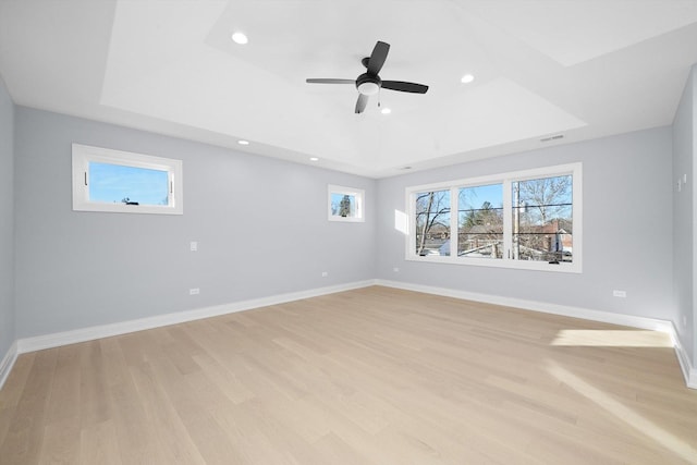 spare room featuring a tray ceiling, light hardwood / wood-style floors, and ceiling fan