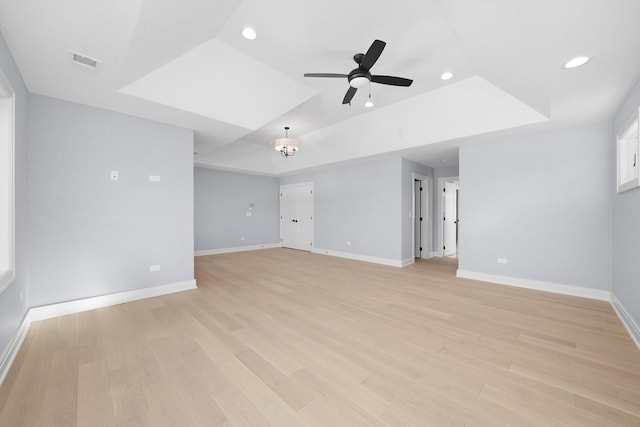 spare room featuring ceiling fan, light wood-type flooring, and a tray ceiling