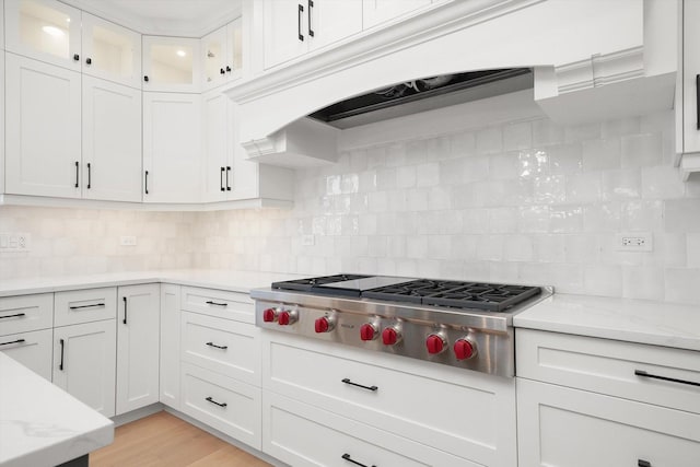 kitchen featuring tasteful backsplash, white cabinets, light stone counters, and stainless steel gas stovetop