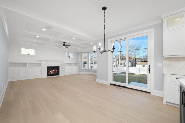 unfurnished living room featuring crown molding, coffered ceiling, ceiling fan with notable chandelier, beamed ceiling, and light wood-type flooring