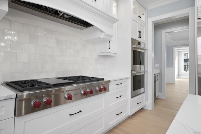 kitchen featuring crown molding, custom exhaust hood, stainless steel appliances, and white cabinets