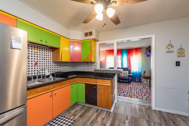 kitchen with dark hardwood / wood-style floors, stainless steel refrigerator, tasteful backsplash, sink, and ceiling fan