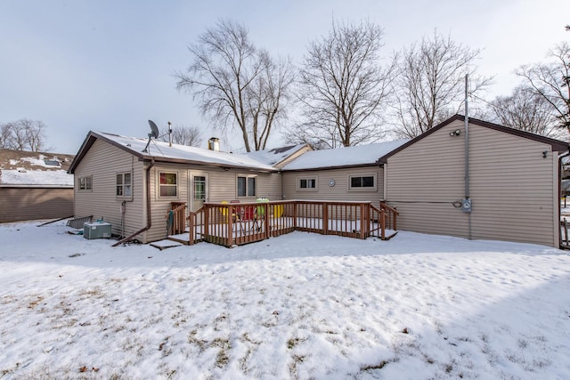 snow covered rear of property with a wooden deck and cooling unit