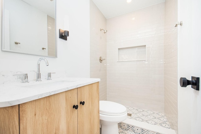 bathroom featuring tiled shower, vanity, and toilet