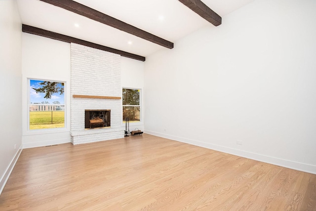 unfurnished living room featuring beam ceiling, a fireplace, and light hardwood / wood-style flooring