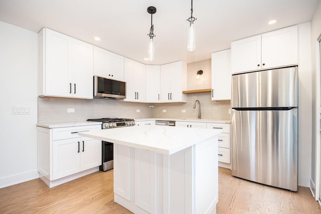 kitchen featuring white cabinetry, stainless steel appliances, a center island, and light hardwood / wood-style floors