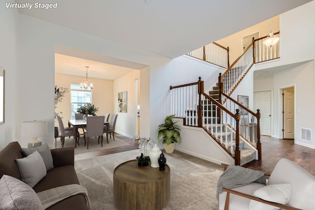 living room with carpet floors, an inviting chandelier, and a towering ceiling