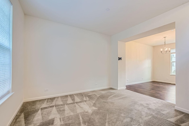 carpeted spare room featuring a chandelier