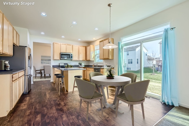 kitchen featuring pendant lighting, a center island, a kitchen bar, dark hardwood / wood-style flooring, and light brown cabinets