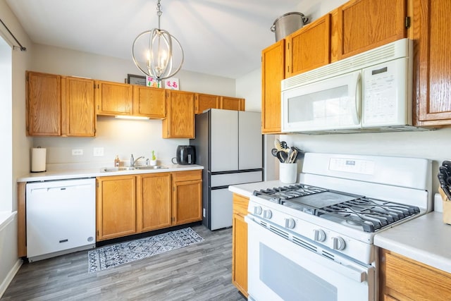 kitchen with hardwood / wood-style floors, sink, hanging light fixtures, a notable chandelier, and white appliances