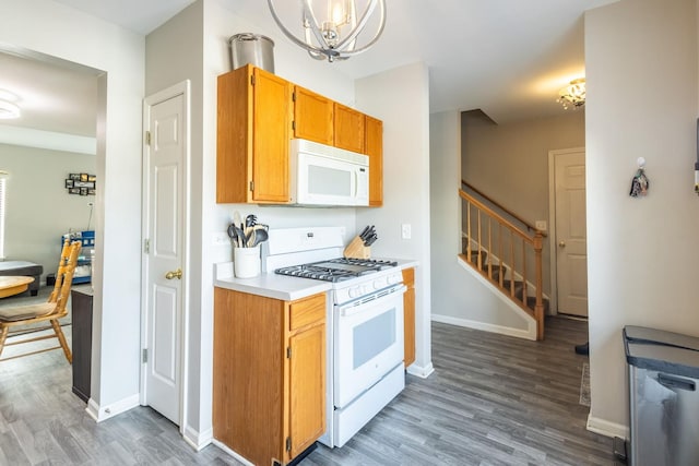 kitchen featuring pendant lighting, a notable chandelier, white appliances, and wood-type flooring