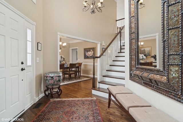 foyer entrance featuring an inviting chandelier, dark wood-type flooring, and a high ceiling