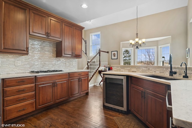 kitchen featuring sink, decorative light fixtures, dark hardwood / wood-style floors, stainless steel gas stovetop, and beverage cooler