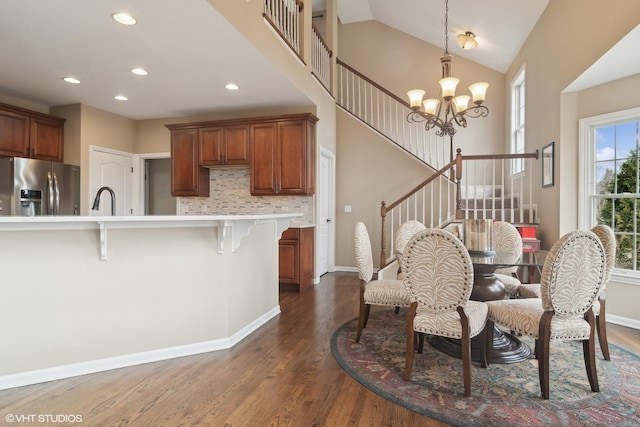 dining space featuring sink, high vaulted ceiling, dark hardwood / wood-style floors, and a chandelier