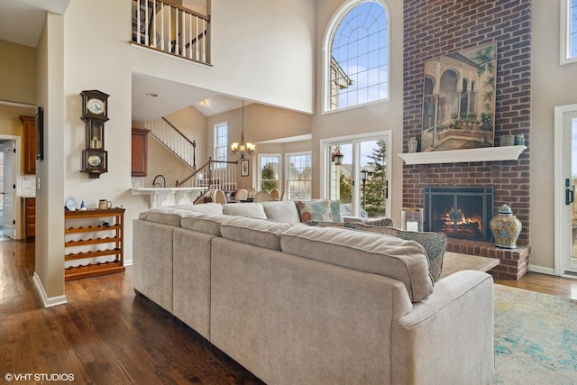 living room with dark wood-type flooring, a fireplace, a high ceiling, and a notable chandelier