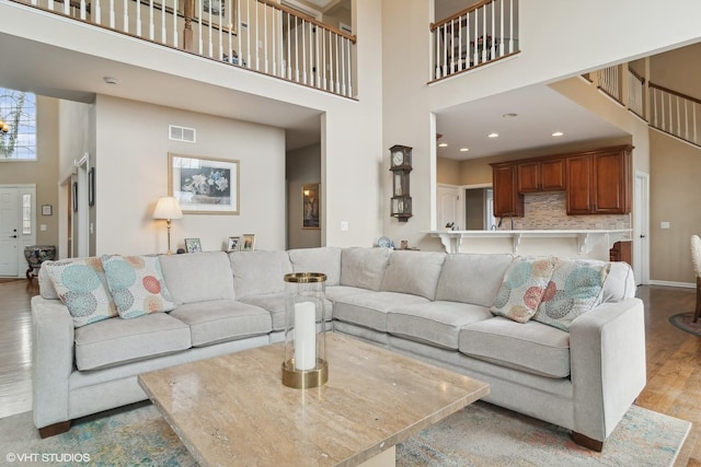 living room featuring a towering ceiling and light hardwood / wood-style flooring