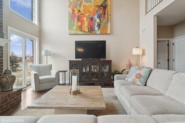 living room featuring a towering ceiling, dark wood-type flooring, and a wealth of natural light