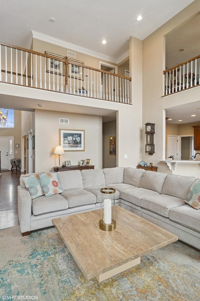 living room featuring crown molding, wood-type flooring, and a high ceiling