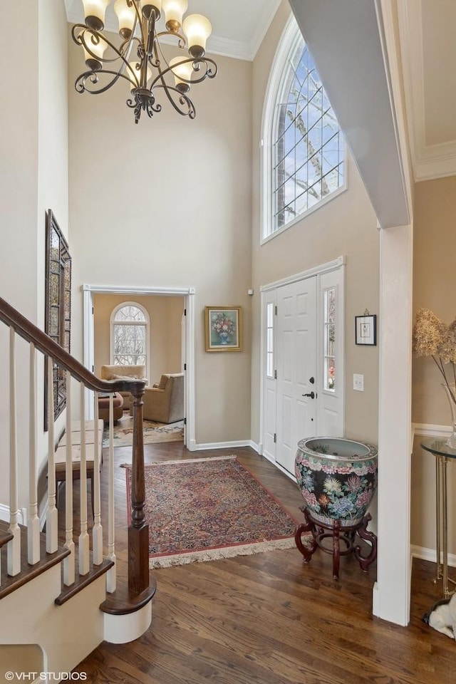 entrance foyer with crown molding, dark hardwood / wood-style floors, a chandelier, and a high ceiling