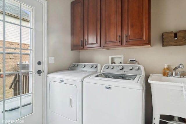 washroom with cabinets, washer and dryer, and sink