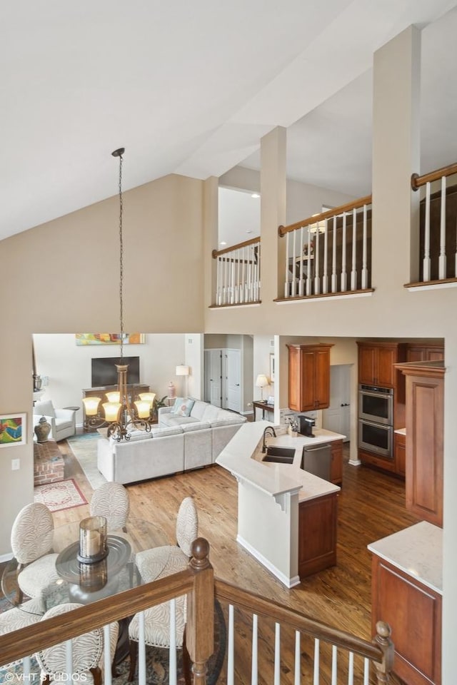 living room with an inviting chandelier, hanging light fixtures, dark wood-type flooring, and an island with sink