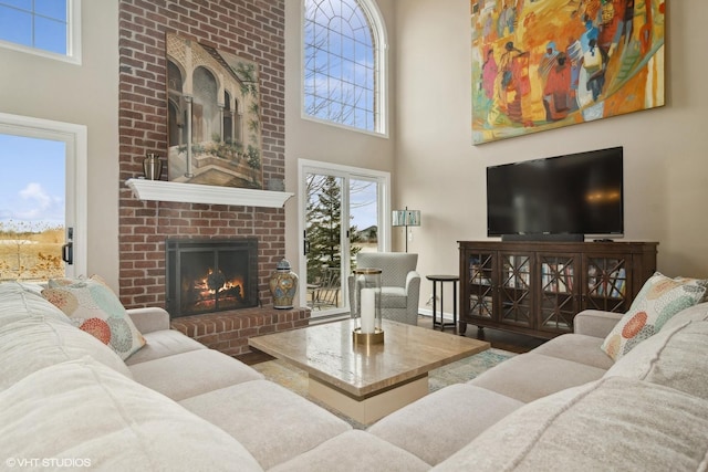 living room with a brick fireplace, a towering ceiling, and hardwood / wood-style floors