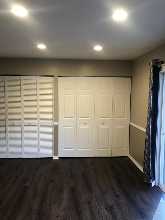 unfurnished bedroom with multiple closets and dark hardwood / wood-style floors