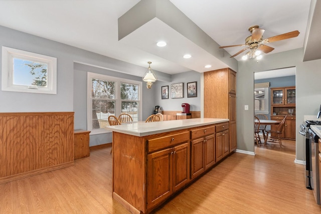 kitchen with hanging light fixtures, light hardwood / wood-style flooring, ceiling fan, and kitchen peninsula