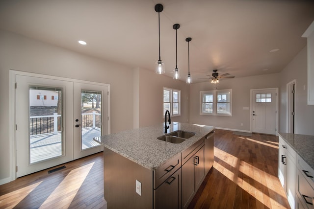 kitchen with pendant lighting, sink, light stone counters, dark wood-type flooring, and french doors