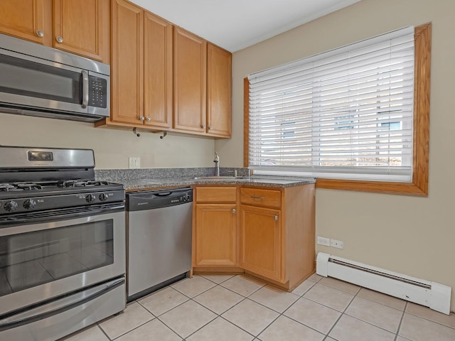 kitchen with sink, light tile patterned floors, baseboard heating, stainless steel appliances, and dark stone counters