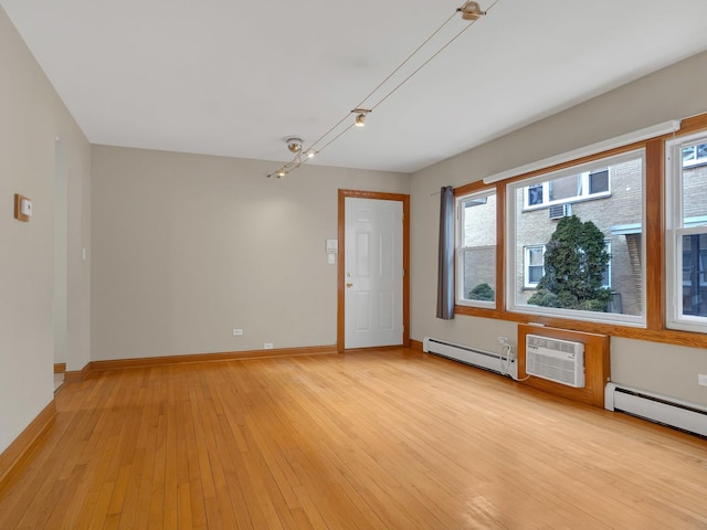 unfurnished room with a healthy amount of sunlight, light wood-type flooring, and a baseboard heating unit