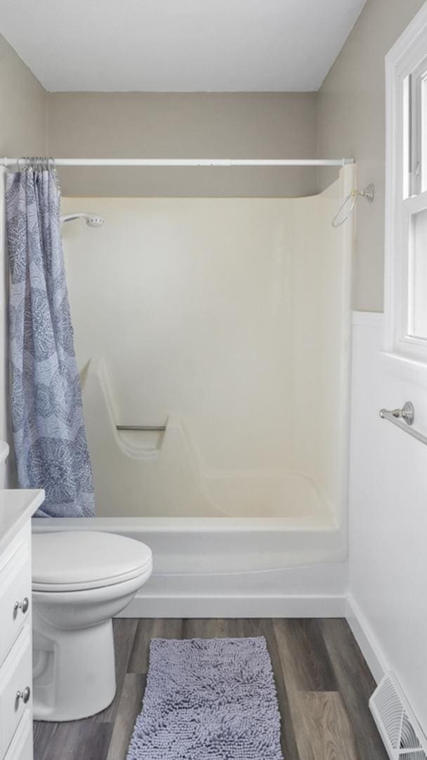 bathroom featuring wood-type flooring, a shower with shower curtain, vanity, and toilet