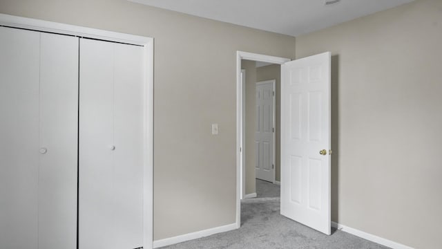 unfurnished bedroom with light colored carpet and a closet