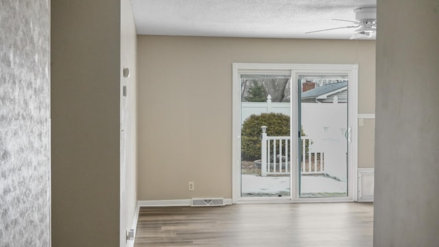 doorway featuring hardwood / wood-style flooring, a textured ceiling, and ceiling fan