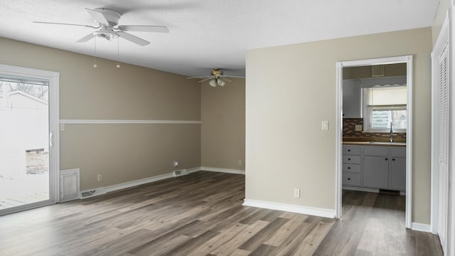 empty room featuring sink, a textured ceiling, dark hardwood / wood-style floors, and ceiling fan