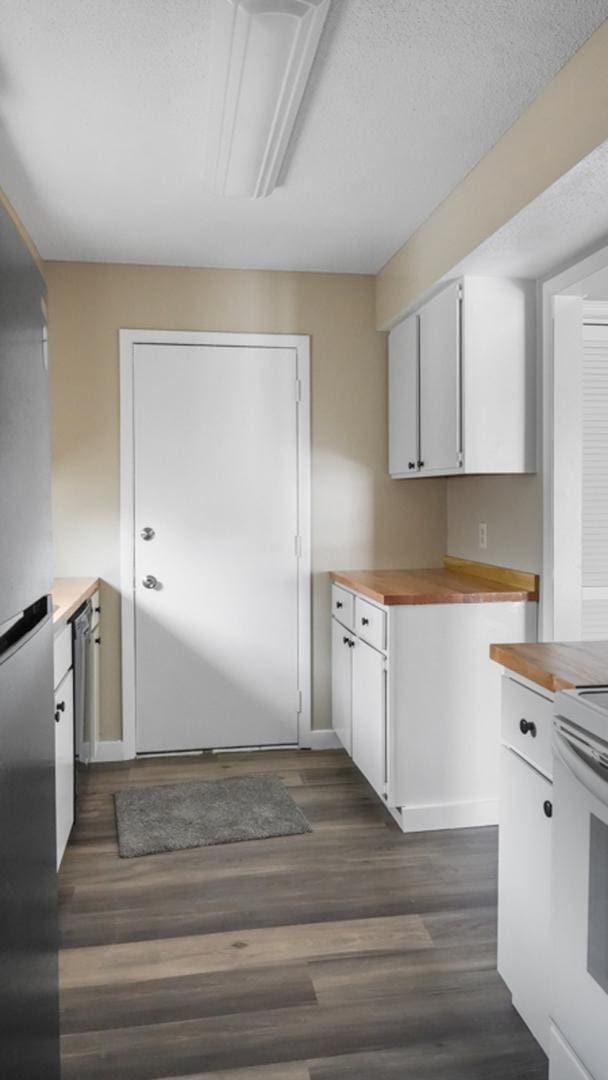 kitchen featuring appliances with stainless steel finishes, wooden counters, dark hardwood / wood-style floors, and white cabinets