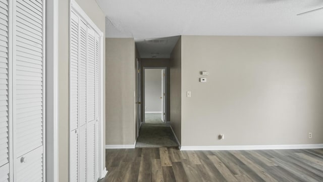 corridor featuring dark wood-type flooring and a textured ceiling