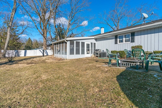 rear view of house featuring a sunroom, a lawn, and an outdoor fire pit