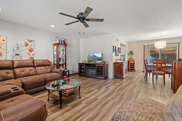 living room with ceiling fan with notable chandelier and light wood-type flooring