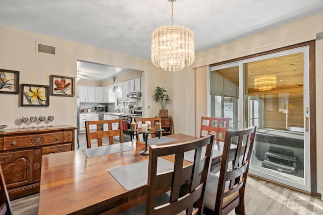 dining room with light wood-type flooring, sink, and a chandelier