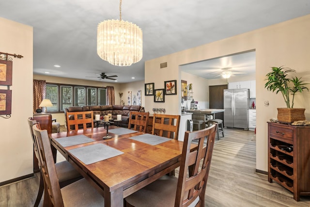 dining room with ceiling fan with notable chandelier and light wood-type flooring