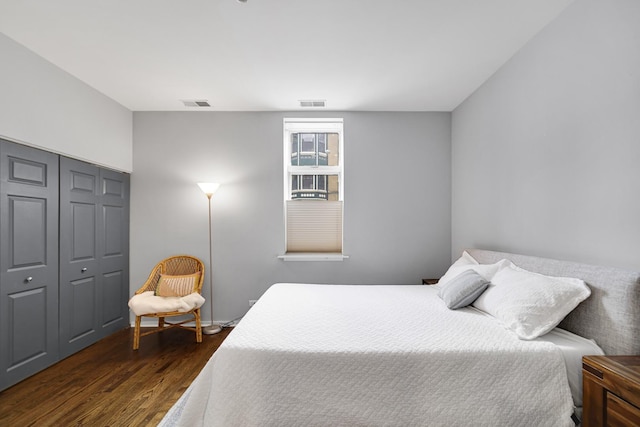 bedroom with dark hardwood / wood-style floors and a closet