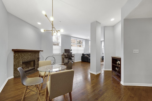 dining space featuring a fireplace, dark hardwood / wood-style floors, and a chandelier