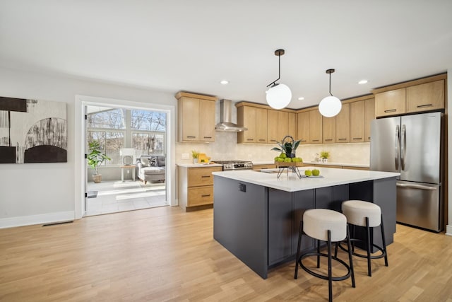 kitchen with wall chimney range hood, stainless steel fridge, stove, hanging light fixtures, and a center island