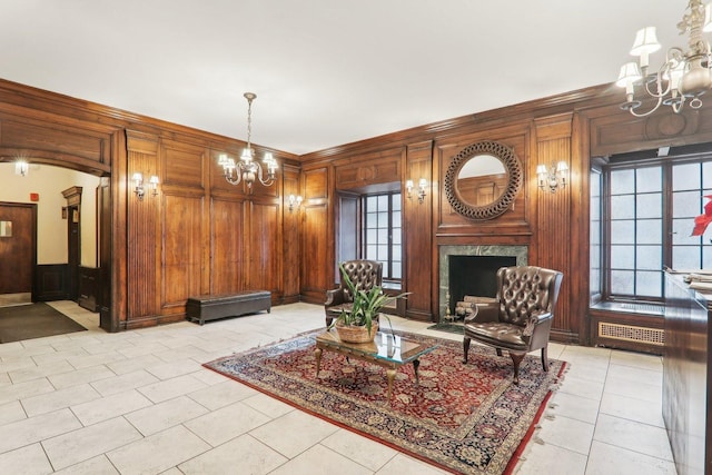 living room with light tile patterned flooring, a high end fireplace, a chandelier, and wood walls