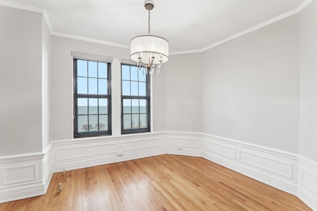 unfurnished room featuring a notable chandelier, hardwood / wood-style flooring, ornamental molding, and a water view